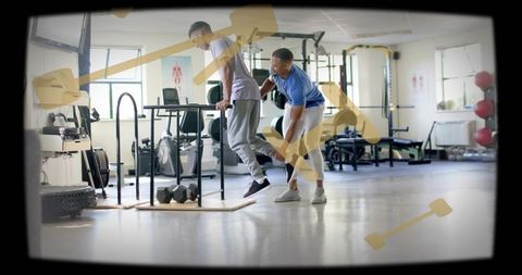 Trainer assisting athlete performing parallel bar dips in bright gym for strength training