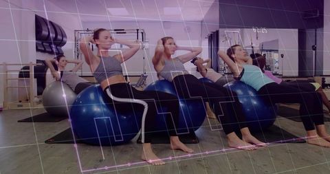 Women performing swiss ball crunches in group core stability class with workout timer