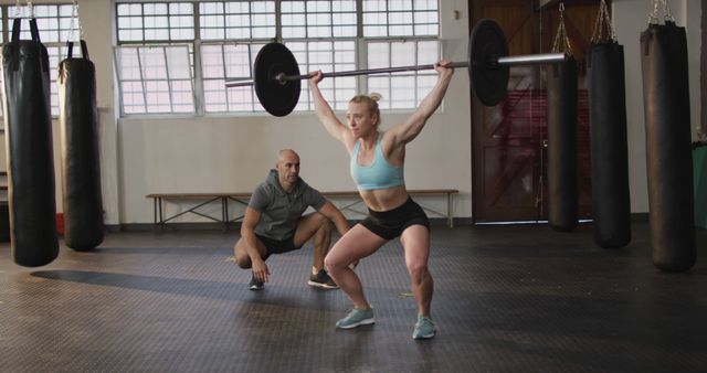 Fit caucasian woman working out with barbell with male trainer at the gym. sports, training and fitness concept