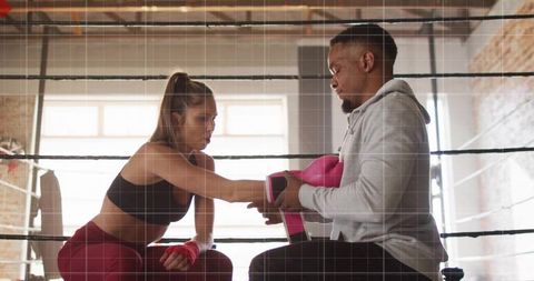 Coach Instructing Athlete with Boxing Gear in Training Ring