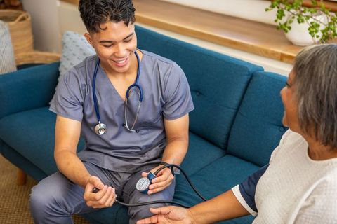 Male nurse conducting home blood pressure measurement on senior woman
