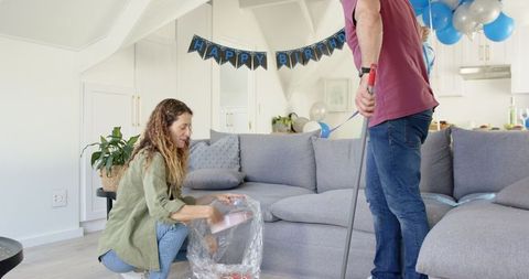 Couple Cleaning Living Room After Birthday Celebration