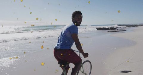 Man enjoying bicycle ride along beach shoreline on sunny day