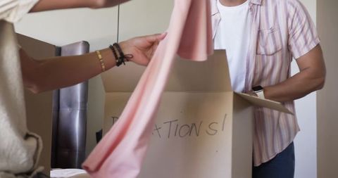 Couple unpacking moving box with pink striped shirt and soft fabric for new home