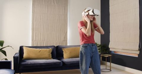 Woman Experiencing Virtual Reality at Home Wearing White VR Headset in Modern Living Room