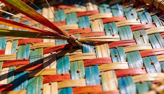 Catching warm light on colorful handwoven palm mat with knotted fibers and stitched joins