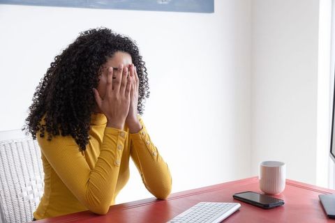 Stressed Woman in Home Office Covering Face