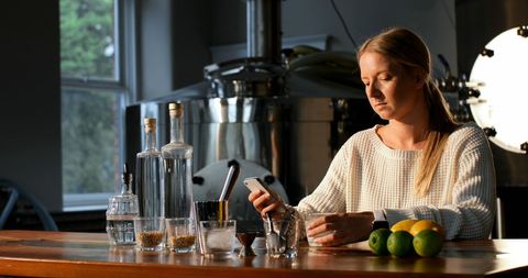 Woman Texting at Bar with Drinks and Citrus in Relaxed Setting - Download Free Stock Images Pikwizard.com