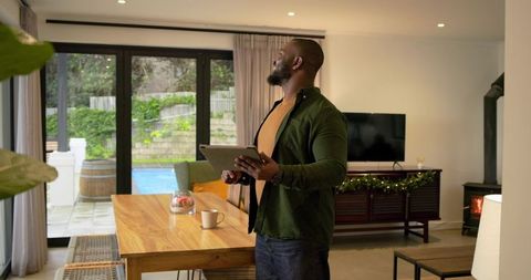 African American Man Inspecting Ceiling with Tablet in Modern Home Dining and Living Area
