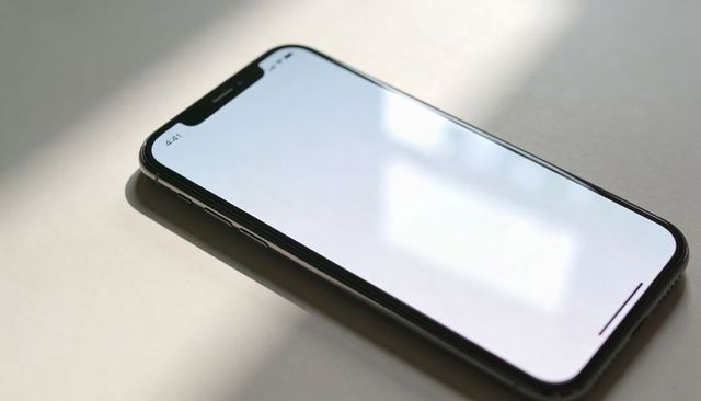 Minimal Modern Smartphone Mockup with Notch and Blank Screen on Tabletop, Sunlit Reflection