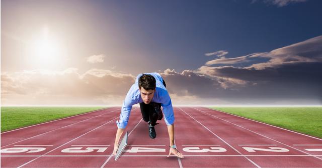 Businessman crouching at starting line of running track under dramatic sky with sunset. Ideal for concepts related to career beginnings, professional competition, motivation, determination and striving for success.
