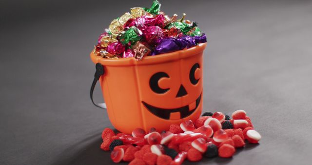 Bright Halloween bucket filled with an assortment of colorful candies, perfect for use in Halloween-themed promotions, advertisements, and festive holiday greeting cards.