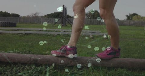 Balancing woman walking on log wearing pink running shoes outdoor fitness training