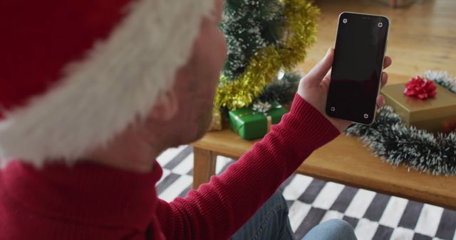 Man in Santa Hat Holding Smartphone During Christmas Celebration - Download Free Stock Images Pikwizard.com