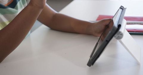 Teen tapping tablet at desk with folio kickstand for remote learning and study