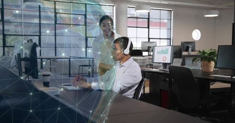 Business professionals collaborating with holographic data visualization in open-plan office