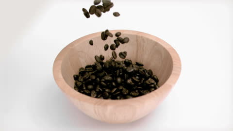 Coffee Beans Falling into Wooden Bowl in Slow Motion