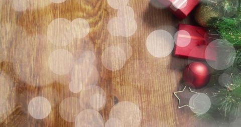 Rustic christmas flatlay featuring red gifts, baubles and fir with bokeh on wood table