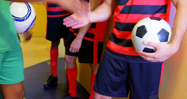 Athletes from opposing soccer teams meeting and shaking hands in a locker room. Promoting sportsmanship and unity before a competitive match. Ideal for illustrating pre-game rituals, team dynamics, and fostering positive attitudes in sports.