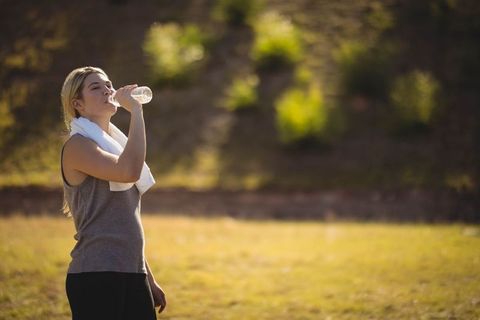 Woman Rehydrating After Outdoor Exercise in Sunny Field