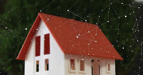 Miniature house with red roof and digital network overlay