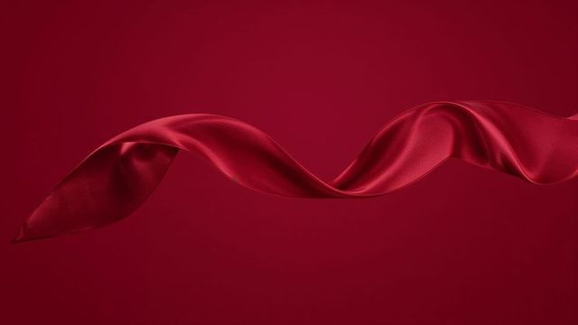 Twisting red satin ribbon in motion on red background