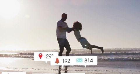 Father swinging daughter on beach at golden hour with social media notification icons