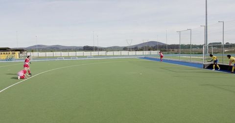 Field hockey players defending goal on artificial turf with wide copy space