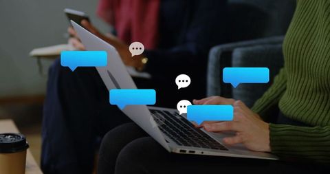 Typing on laptop with floating chat bubbles in coworking lounge