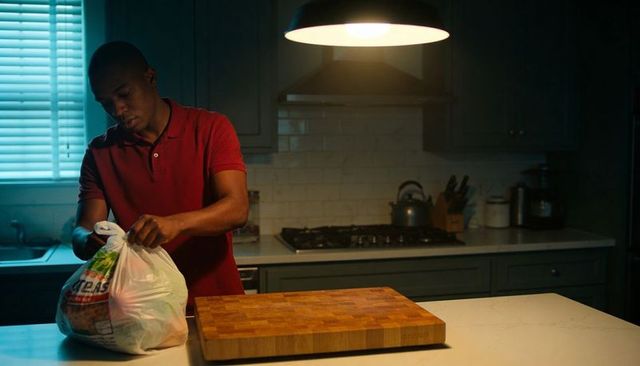 Man unpacking grocery bag on modern kitchen island under pendant light