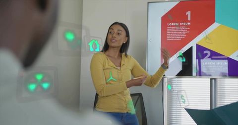 Businesswoman presenting with augmented reality icons in collaborative office meeting
