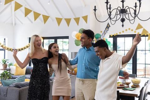 Diverse friends celebrating at home party with balloon decor
