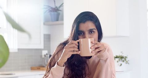 Middle-aged woman sipping tea in cozy modern kitchen ambiente