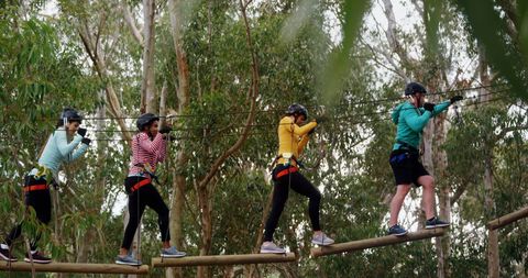 Diverse Group Navigating High Rope Course in Adventure Park