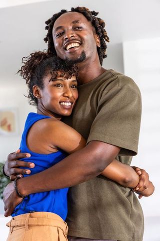 African american couple embracing and smiling in cozy home portrait, closeup hug