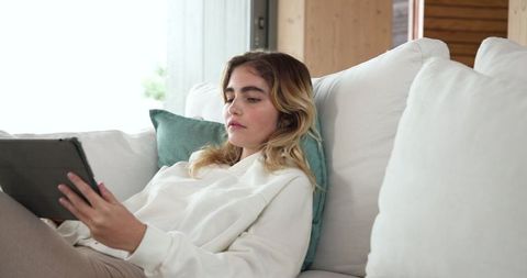 Woman Relaxing on Comfortable Sofa with Tablet in Modern Living Room