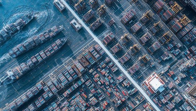 Overhead container terminal at coastal port showing stacked containers and gantry cranes
