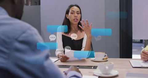 Businesswoman leading team discussion with chat bubble overlays in modern office meeting