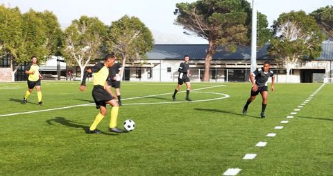 Soccer Players in Yellow Jerseys Practicing on Sunny Field