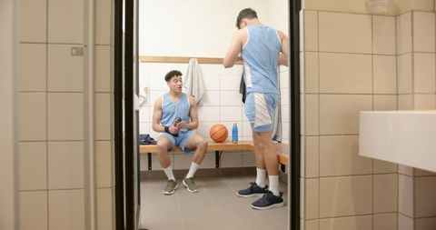 Teammates preparing for game in locker room with basketball gear