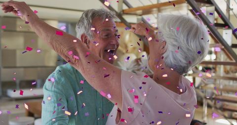 Joyful Senior Couple Dancing as Confetti Falls Indoors