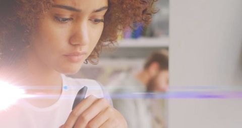 Pensive woman holding pen with creative light flare