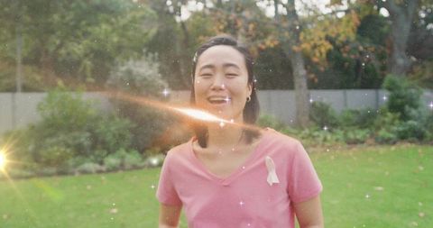 Smiling Woman with Awareness Ribbon Surrounded by Sparkles in Backyard