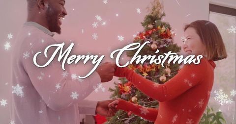 Couple exchanging red stocking by christmas tree, smiling and celebrating cozy holiday warmth