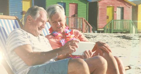 Senior Couple Relaxing on Beach with Tablet