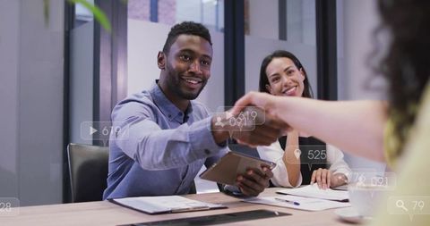 African american businessman shaking hands while holding tablet in modern boardroom meeting