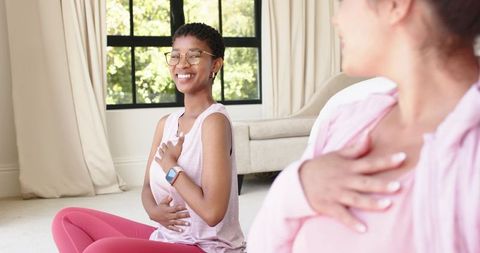 Smiling woman practicing guided breathwork with friend at home for calm and wellness
