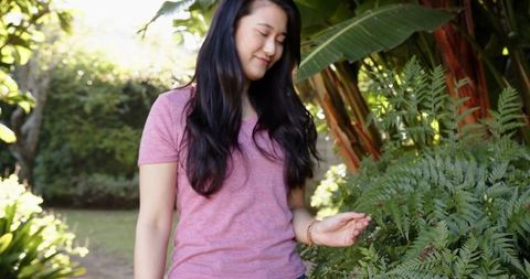 Asian Woman Enjoying Peaceful Moment in Lush Tropical Garden