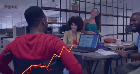 Diverse team collaborating around laptop with charts and graphs in modern open office hub