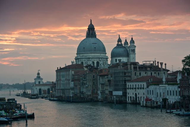 Showcases a breathtaking sunset over the iconic Santa Maria della Salute in Venice, Italy. Perfect for travel articles, brochures, and websites highlighting European destinations, historical landmarks, or inspirational landscapes. Ideal addition to materials focusing on architecture, heritage tourism, and photography of scenic cityscapes.